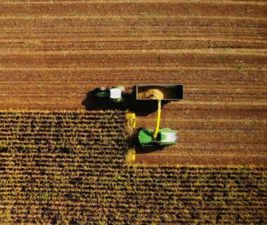 Aerial view of modern agricultural machinery harvesting crops in a field.