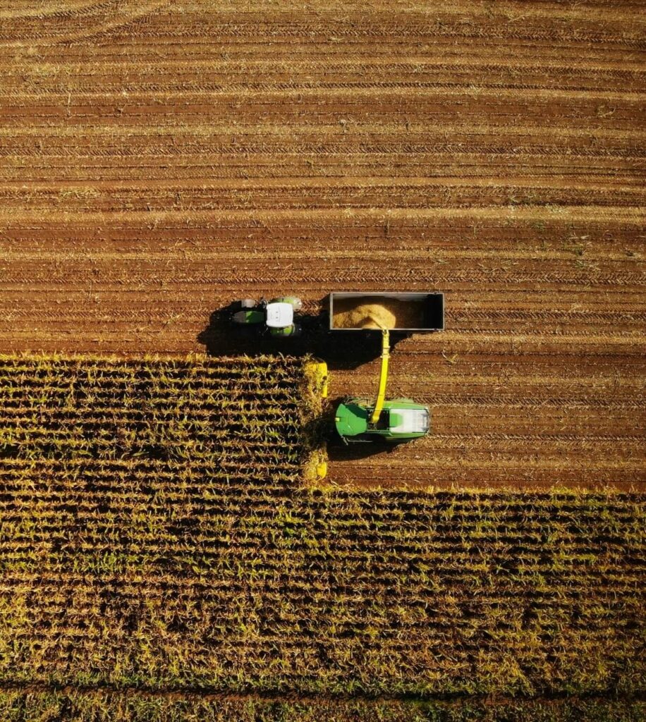 Aerial view of modern agricultural machinery harvesting crops in a field.